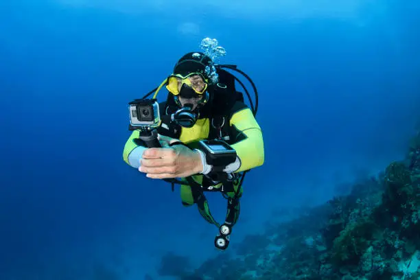 Male scuba diver using an action camera to take some underwater shots.