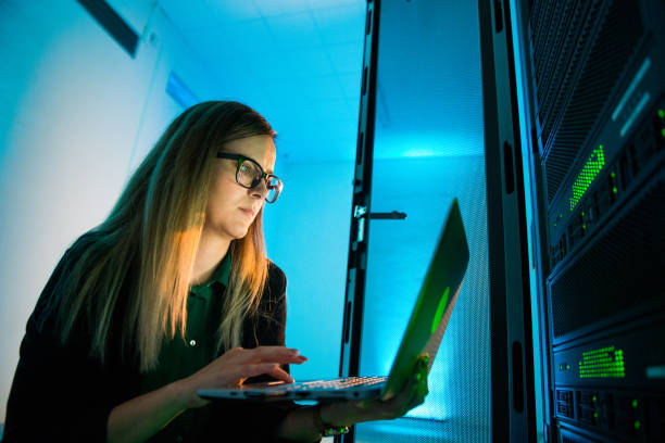 Female IT Professional Working With Laptop in Supercomputer Room
