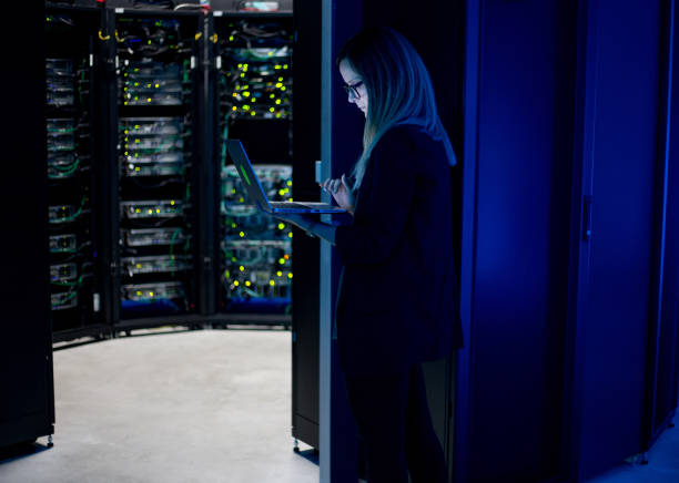 istock Female IT Professional Working in Server Room With Laptop 1073009054