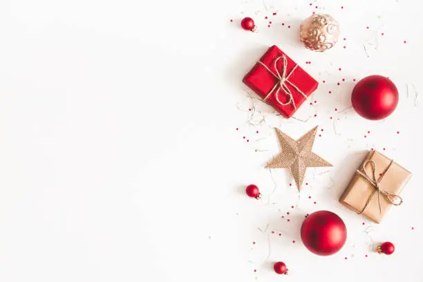 Photo of Christmas composition. Christmas gifts, red and golden decorations on white background. Flat lay, top view, copy space