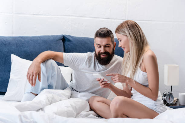 istock happy couple in love using smartphone in bed in morning 1073021740