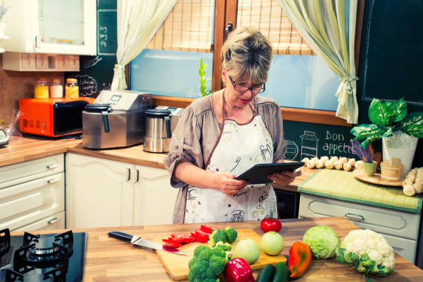 istock Mature  woman using digital tablet while cooking in the kitchen. 1073022252