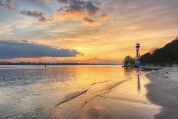 Sunset at the lighthouse on the Elbe in Hamburg Colourful sunset on the Elbe beach of the rissener Ufer lighthouse near Hamburg sonne stock pictures, royalty-free photos & images