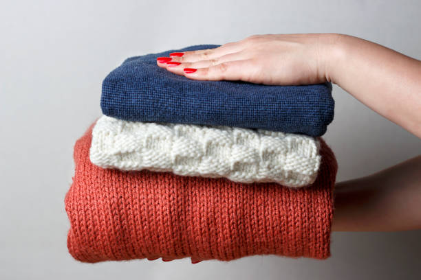 istock Female hands with a red manicure holding a stack of knitted woolen things, front view, close-up 1073028680
