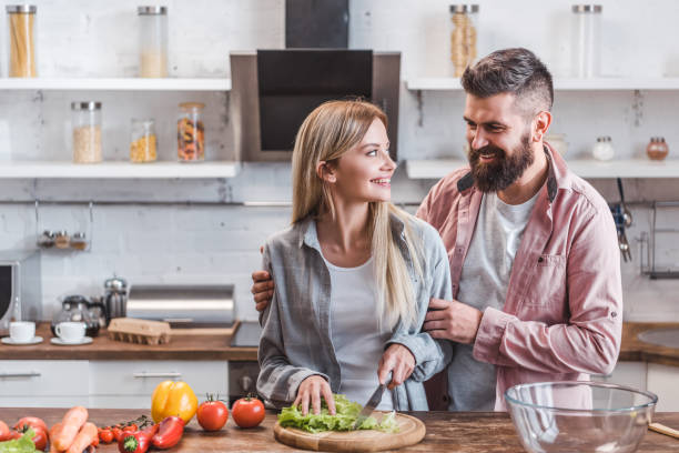 istock Cheerful and smiling couple preparing dinner in kitchen 1073032536