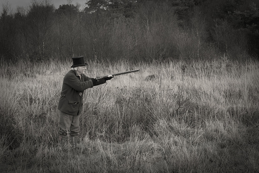 old photograph look of a Gentleman wearing top hat shooting with a muzzle loading shot gun
