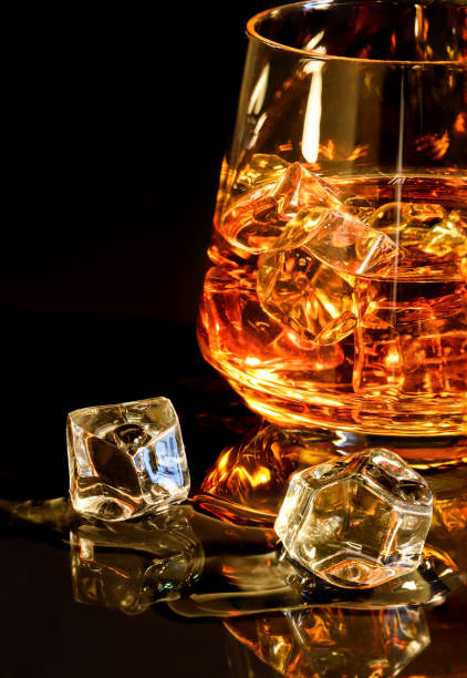 istock Whiskey with ice in glass on black background 1073043794