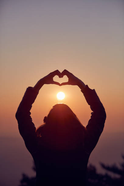 istock Girl making heart - shape sign with hands at sunset / sunrise time. 1073045526