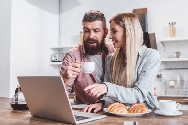 istock cheerful couple having breakfast and using laptop in morning 1073045884