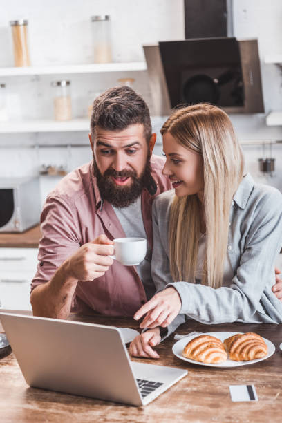 istock attractive woman pointing at laptop screen while happy man drinking coffee 1073045892
