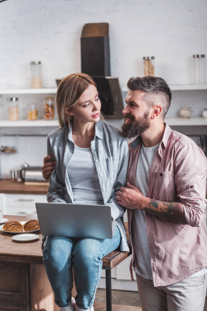 istock young couple with laptop hugging at kitchen in morning 1073045896