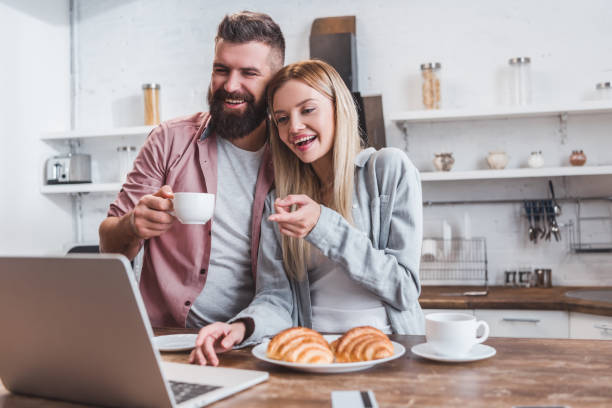 istock smiling woman pointing at laptop screen while man drinking coffee 1073046464