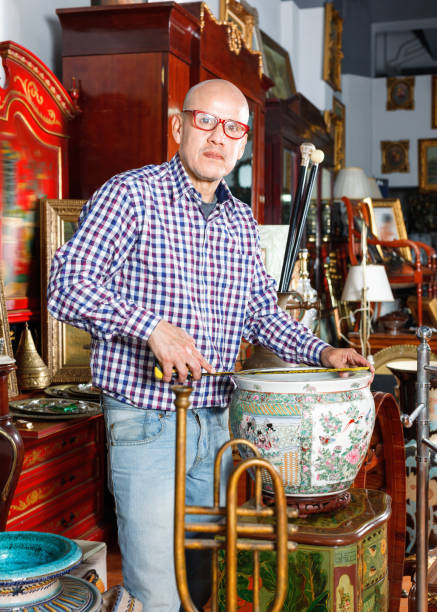 istock Experienced appraiser of antiques shop measuring antique vase while determining value 1073048422
