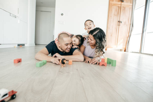 Couple and kids playing toys lying on the floor,.