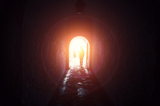 Light in end of tunnel with silhouettes of people, way to hope and freedom concept
