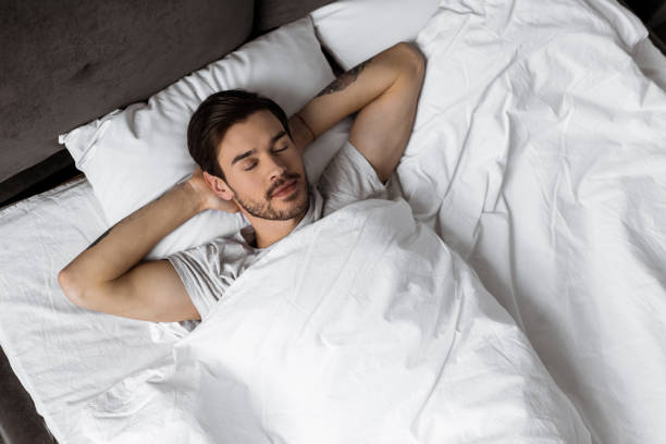 istock top view of handsome bearded young man sleeping with hands behind head in bed 1073071150