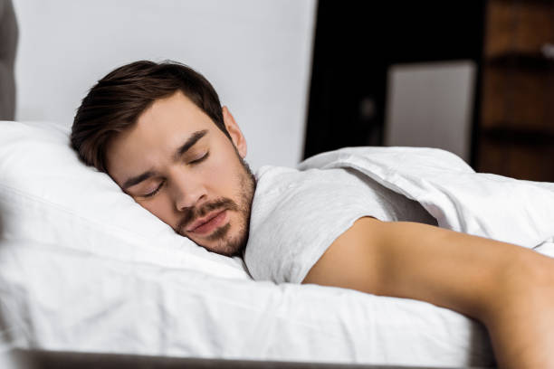 istock handsome bearded young man sleeping in bed at home 1073071178