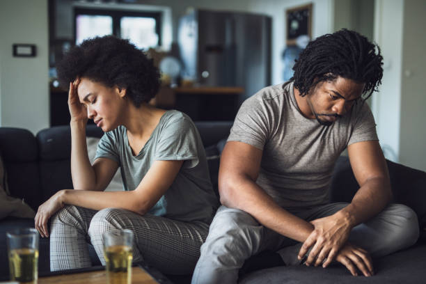 African American couple having problems in their relationship at home. Young black couple feeling sad after arguing on sofa at home. relationship breakup stock pictures, royalty-free photos & images
