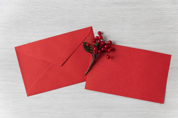 istock Red envelope and greeting card with holly berries on white wooden background 1073088664
