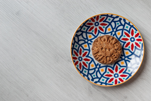 Homemade whole wheat biscuit on colorful saucer with geometric patterns