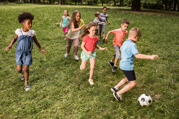 istock Group of playful children having fun while playing soccer in nature. 1073099512