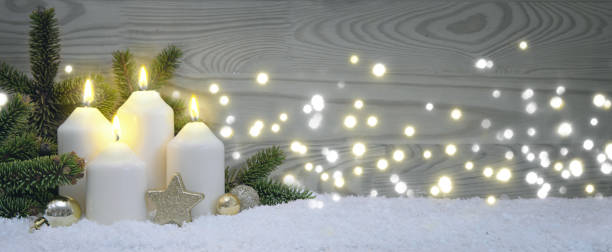 Four burning Advent candles with golden decoration and white snow. stock photo
