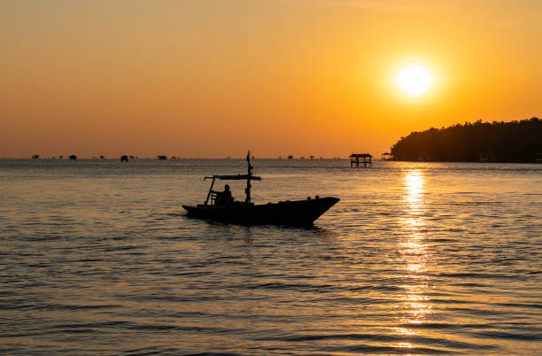 silhouette boat in the sea with sunrise in the sky stock photo