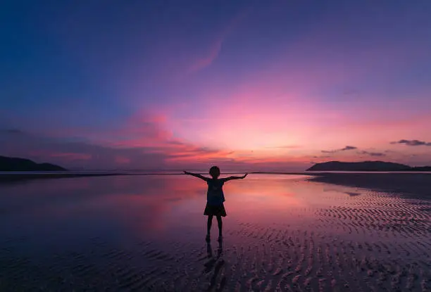 One girl standing and stretch the arm  on the beach with beautyfull sunset