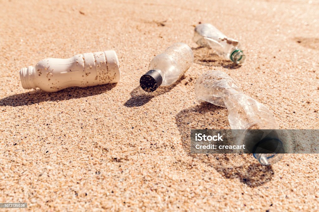 Coastal Plastic Pollution Coastal Plastic Pollution. a selection of Plastic bottles on the sand of a bright sunny beach. Staged photograph. Beach Stock Photo