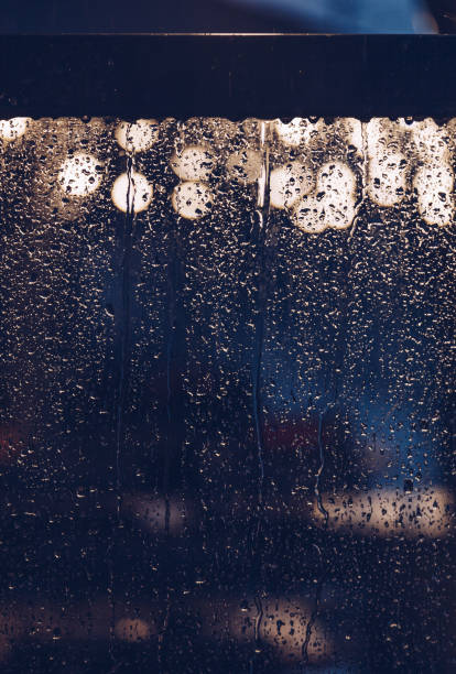 istock nigh light drop water on glass whit light in the street. 1073139680