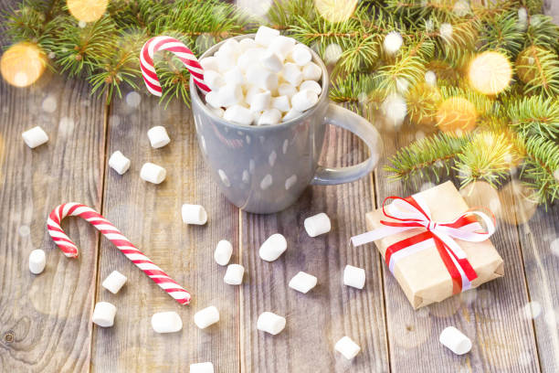 istock Hot coffee chocolate with marshmallow on rustic wooden table background, candy canes gift boxes fir tree with snow 1073145846