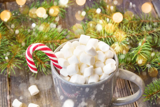 istock Hot coffee chocolate with marshmallow on rustic wooden table background, candy canes gift boxes fir tree with snow 1073145848