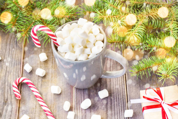 istock Hot coffee chocolate with marshmallow on rustic wooden table background, candy canes gift boxes fir tree with snow 1073145854