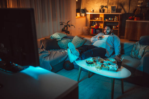 istock Overweight guy changing channels  in living room 1073149858