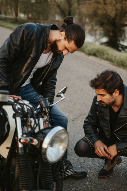 Two  male friends looking seriously at motorcycle  on the road