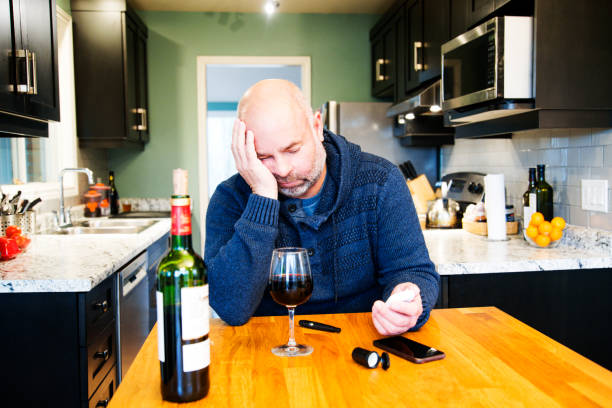 Mature diabetic patient at home testing his blood sugar. A topic on alcohol and diabetes. Mature diabetic patient at home testing his blood sugar and drinking alcohol. A topic on alcohol and diabetes. diabetes and alcohol stock pictures, royalty-free photos & images
