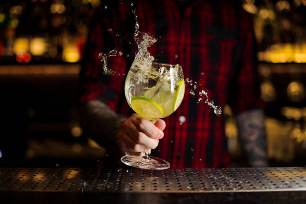barman fazendo o respingo de um gin tónico cocktail com fatias de limão - tattoo shirt caucasian one person - fotografias e filmes do acervo