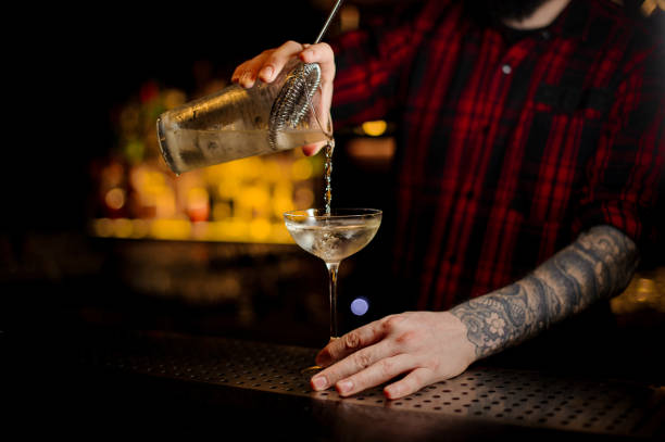 istock Professional bartender pouring a Twinkle achoholic cocktail drink from the measuring cup 1073167852