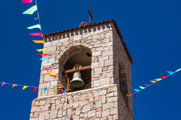 Bell Tower and Bell, Colourful Flags and Blue Sky, the Church of Saint Antonio of Padua in Baia Sardinia, & Blue Sky. Baia Sardinia, Gallura, Sardinia, Italy. - fotografia de stock