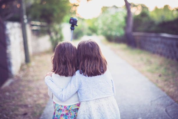 istock Identical twins sisters walking and taking selfie with action camera. 1073189196