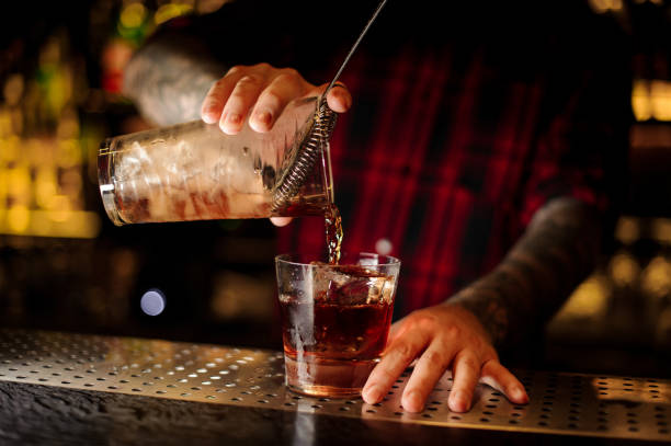 istock Mixologist pouring fresh strong whiskey cocktail into a glass 1073194808