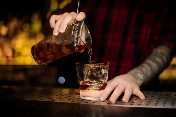 istock Bartender pouring fresh strong whiskey cocktail into a glass 1073195848