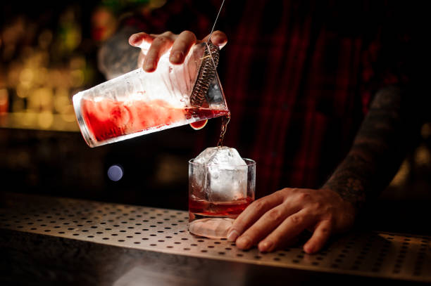 istock Barman pouring fresh strong red whiskey cocktail into a glass 1073196700