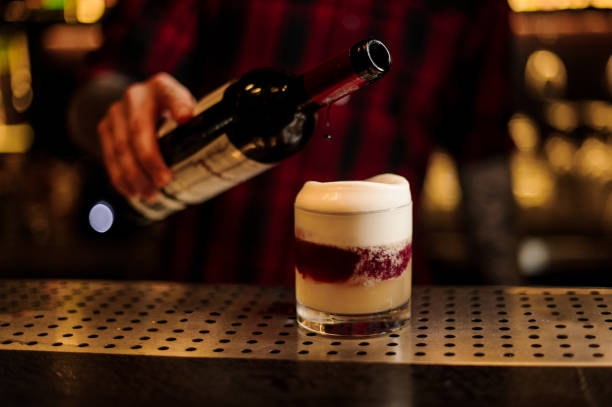 istock Bartender pouring red wine into a glass with fresh sweet cocktail 1073196790
