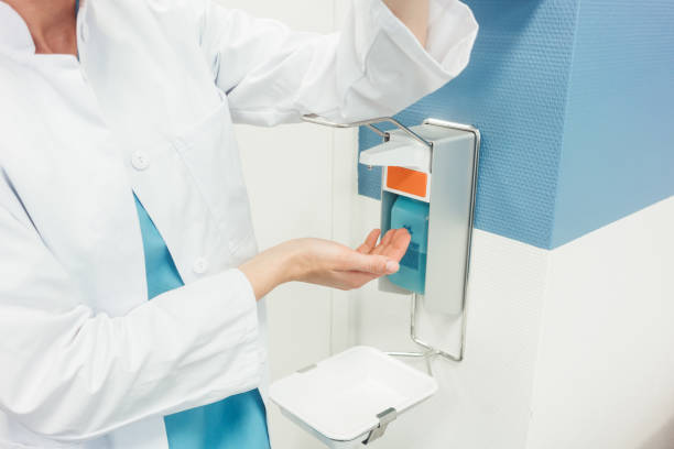 Doctor cleaning and disinfecting her hands in hospital stock photo