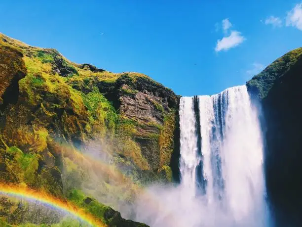 a colorful image of a waterfall, colliding with the end of two rainbows
