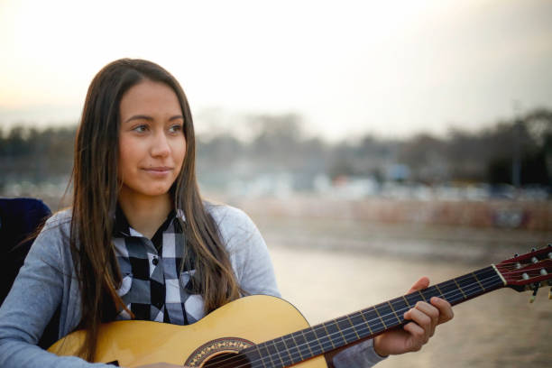 istock Young woman playing guitar outdoors 1073200590