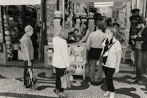 Lisbon, Portugal - June 1, 2018: A seamstress sews outside a shop in the Rua Augusta street in Lisbon downtown.