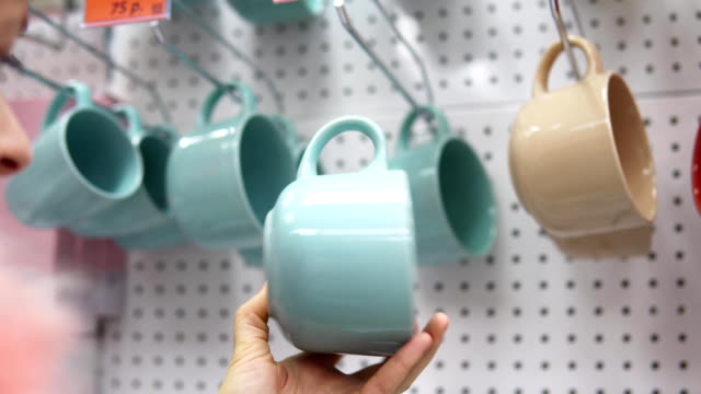 Someone picks a big ceramic cup in the supermarket.