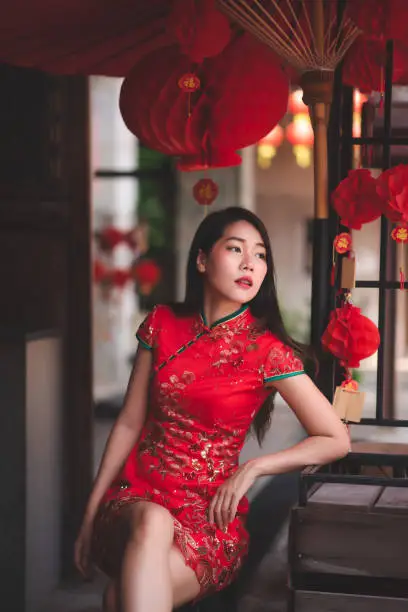 Asian Chinese Woman Wearing Cheongsam Traditional Red Dress Siting on Chair Fashion Posting Chinese New Year